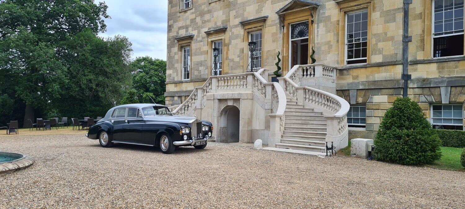 luxury car parked on gravel in front of fancy building