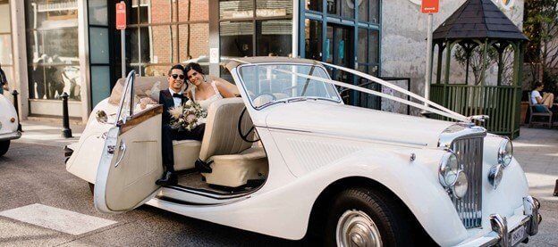 Amazing white car with bride and groom in the back