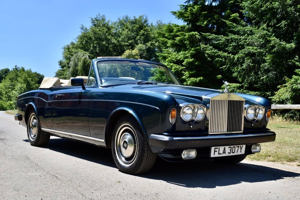 Rolls Royce convertible parked with trees behind