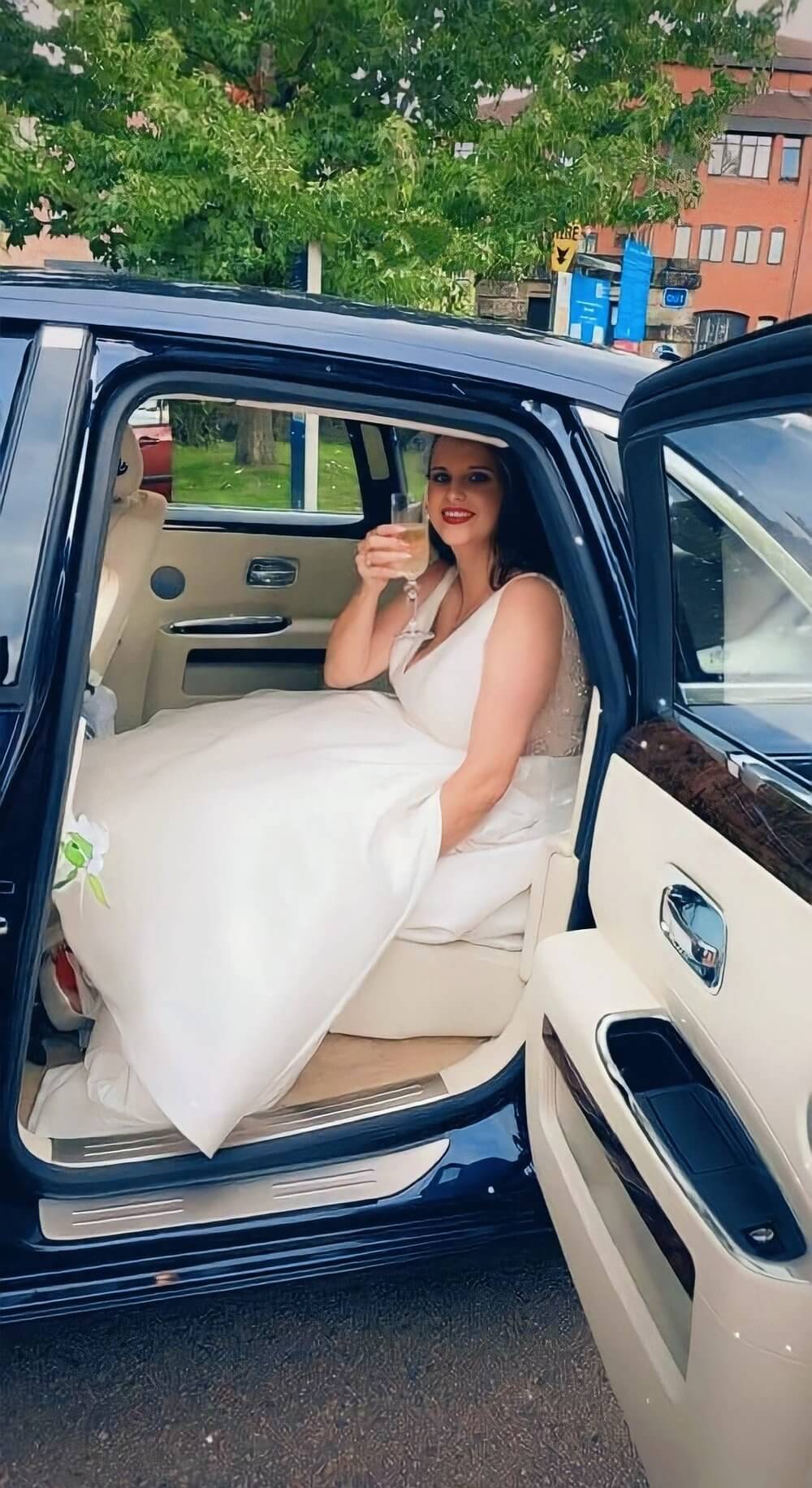 bride smiling with glass of champagne in the back of car