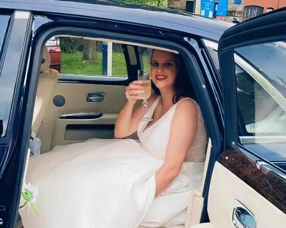 bride with glass of champagne in back of car